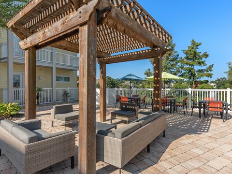 a patio with couches and a wooden pergola